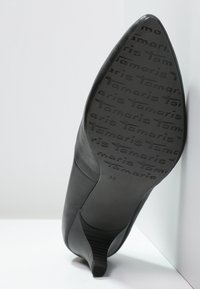 Svart högklackad sko med spetsig tå, slät läderöverdel, texturerad gummisula med "Tamaris"-logotyp, storlek 39.