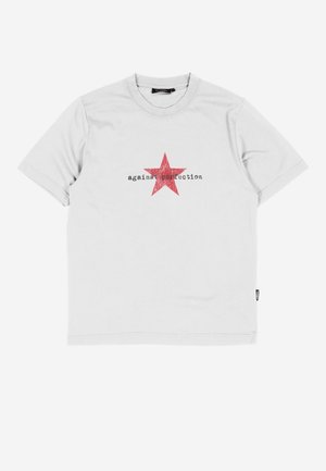 Valkoinen lyhythihainen T-paita, jossa on punainen tähti ja mustalla painettu teksti "against perfection" rinnan kohdalla.