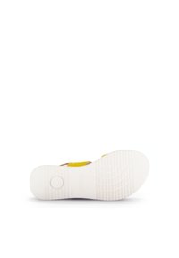White rubber shoe sole with a textured pattern. Yellow upper strap detail near the midsection. Round logo embossed on the heel area.