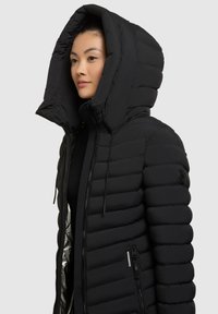 Schwarze Daunenjacke mit einer großen, strukturierten Kapuze. Merkmale sind das horizontal gestepptes Design, ein vorderer Reißverschluss und eine seitliche Reißverschlusstasche.