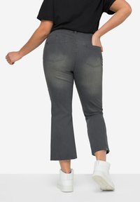 Jean cropped gris avec un délavage, ourlet effiloché et deux poches arrière, associés à des baskets montantes blanches.