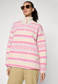 Fleece pulover u krem boji s ružičastim i lavandom geometrijskim uzorcima. Ima visoki ovratnik i polu-zip prednji dio. Glatka tekstura.