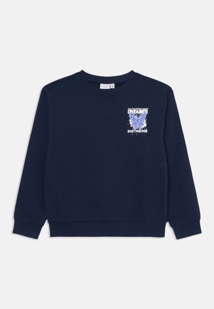 Marineblå genser med ribbede mansjetter og nederkant. Har et sommerfugl-grafikk og teksten "DREAMER STAY POSITIVE" på fronten. Myk stoffstruktur.