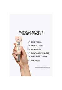 Hånd som holder en tube av IT Cosmetics CC+ Nude Glow-krem med SPF 40, som fremhever kliniske forbedringer i lysstyrke, tekstur, fylde, tone, porer og mykhet.