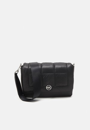 Sac en bandoulière noir matelassé en nylon, avec une bandoulière et du matériel en argent, présentant un logo MK circulaire à l'avant.