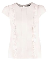 Bílé tričko s krátkým rukávem, které má vertikální volány po stranách, kulatý výstřih a detail na zadní straně ve tvaru klíčové dírky. Hladká textura látky.
