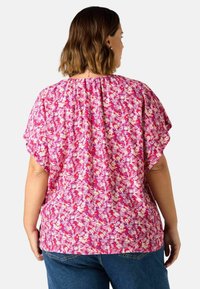 Blommig blus med korta volangärmar, med en rosa bas och mönster av färgglada blommor. Samlad detalj bak, mjukt tyg, avslappnad passform.