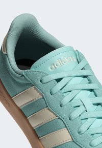 Light blue suede sneaker featuring white leather stripes, textured surfaces, and a gum rubber outsole. Laces and branding in a coordinating color.