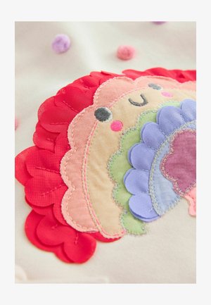 Kleurrijke geborduurde patch met een glimlachend leeuwontwerp en gelaagde bloemblaadjes in rood, roze, groen en blauw tegen een beige achtergrond.