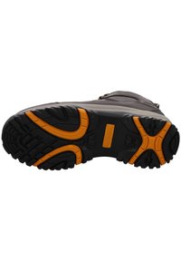 Suela de bota de goma negra con diseño texturizado y acentos naranjas, que cuenta con un diseño grueso y resistente para mejorar la tracción y la estabilidad.
