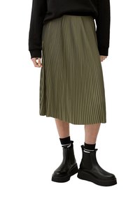 Falda plisada verde oliva hecha de un tejido ligero, con un diseño fluido. Combinada con botas de tobillo negras robustas y calcetines oscuros.
