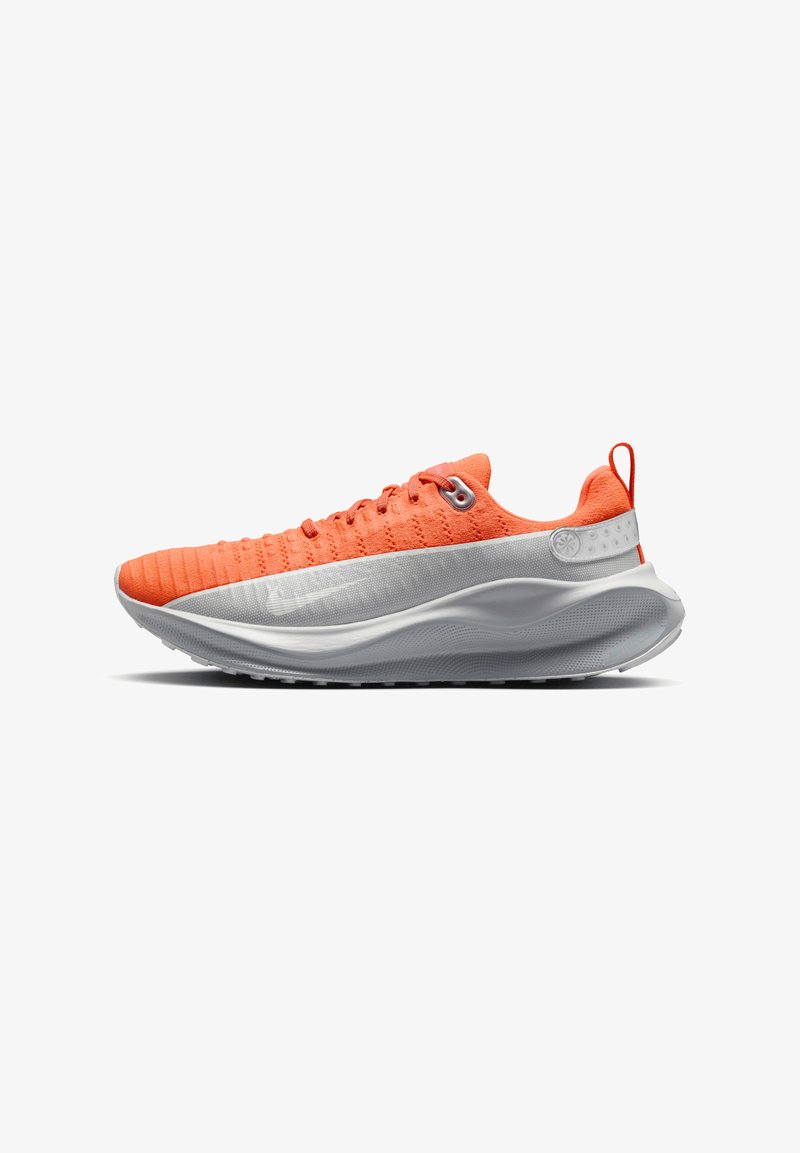 Scarpa da corsa arancione con tomaia testurizzata, suola intermedia bianca e suola esterna nera. Presenta un design con lacci e un'etichetta sul tallone.