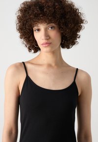 Schwarzes ärmelloses Top mit dünnen Trägern; glattes Baumwollmaterial; taillierte Passform; minimale Nähte; einfacher und klassischer Stil.