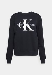 Black sweatshirt with long sleeves, round neck, and ribbed cuffs. Features large white "CK" logo and "calvin Klein Jeans" text across the front.