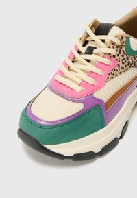 Multicolored sneaker featuring green, pink, purple, and tan panels, mesh texture, chunky sole, and contrast laces with leopard print accents.