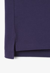 Camisa de algodón púrpura con un tejido texturizado, aberturas laterales en el dobladillo y bordes bien cosidos.