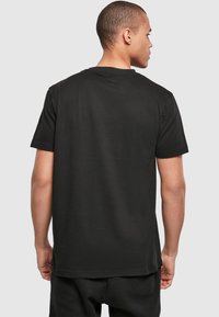 Zwarte katoenen t-shirt met een ronde halslijn, korte mouwen en een rechte zoom. De achterkant toont een gladde stofstructuur zonder patronen.