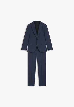 Costume bleu marine avec une veste à boutonnage simple, des revers en notch et un pantalon assorti. Fabriqué en tissu texturé, il est doté de deux poches avant et de manches à boutons.