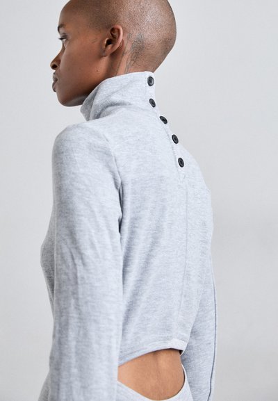 Grijze longsleeve pullover met hoge kraag. Heeft een uitsnijding bij de taille en zwarte knopen langs de achterkant. Zachte, gestructureerde stof.