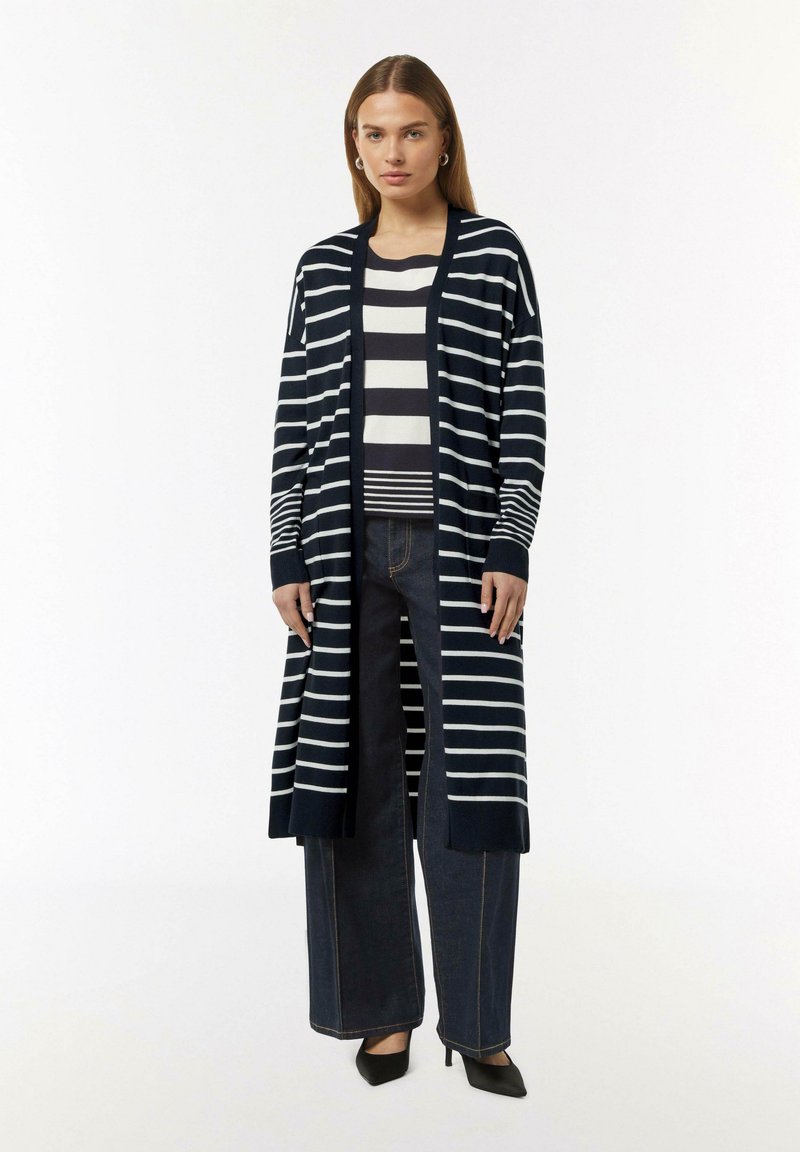 Navy- und weiße gestreifte lange Strickjacke mit offener Front, langen Ärmeln und gerippten Bündchen, kombiniert mit einem gestreiften Oberteil und dunklen weit geschnittenen Jeans.