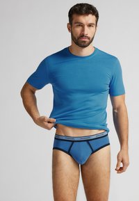 Blaues Baumwoll-T-Shirt mit Rundhalsausschnitt, kombiniert mit blauen Herrenunterhosen, die einen kontrastierenden Bund und eine enganliegende Passform bieten und eine glatte Textur aufweisen.