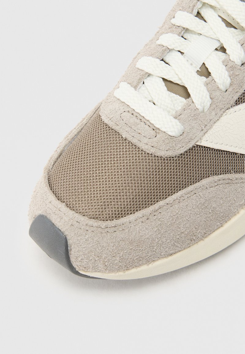 Wildleder- und Mesh-Sneaker in Hellbraun mit weißen Akzenten. Verfügt über eine runde Zehenpartie und flache Schnürsenkel, mit einer grauen Gummisohle.