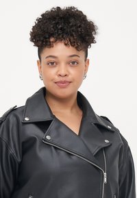 Black faux leather jacket featuring a wide collar, zip closure, and silver hardware accents. The jacket has a relaxed fit and textured surface.