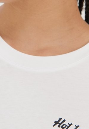 White cotton t-shirt featuring a crew neckline and black text saying "Hot". Smooth fabric texture with minimal design details.