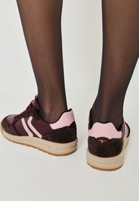 Purple and pink sneakers with suede and synthetic materials, featuring contrasting stripes, a textured heel, and a beige sole.