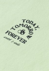 Tessuto verde chiaro con texture morbida, caratterizzato da testo stampato nero: "OGGI, DOMANI, & PER SEMPRE" e "stitch & soda" in un carattere grassetto.