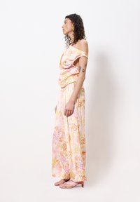 Fließendes Blumenkleid in sanften Rosa- und Gelbtönen, mit einem schulterfreien Design, lockerer Passform und zarten Blumenmustern sowie Seitenschlitzen.