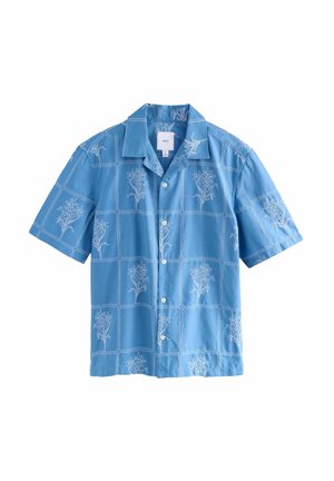 Camicia azzurra a maniche corte con ricami floreali bianchi a motivi quadrati, chiusura con bottoni e colletto classico.