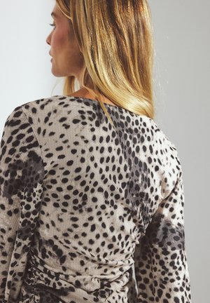 Long-sleeve dress in a soft fabric featuring a beige base with black and brown spotted pattern, with ruching detail at the side.