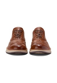 Scarpe da dress in pelle marrone con dettagli brogue, punta rotonda e chiusura con lacci. Suola contrapposta con leggera texture e bordo rialzato.