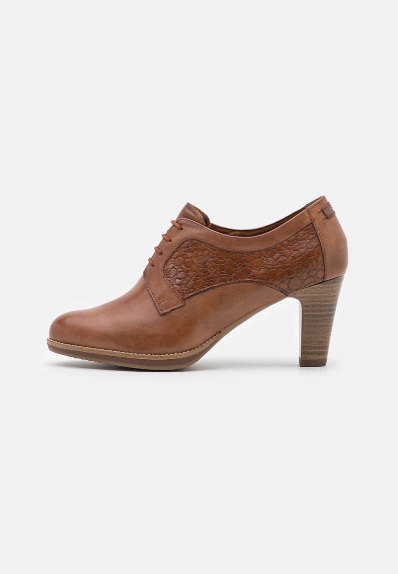 Botín de cuero marrón hasta el tobillo, con un panel lateral texturizado, diseño con cordones y tacón apilado. Acabado suave y forma de punta redonda.