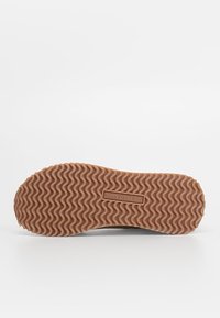 Semelle d'une chaussure avec un motif ondulé et le logo "U.S. Polo Assn." embossé au centre sur un fond clair.