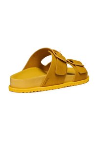 Sandalo giallo in suede con due cinturini regolabili a fibbia, suola in gomma piatta e dettagli laterali ritagliati per la traspirabilità.