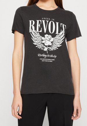 Schwarzes T-Shirt mit kurzen Ärmeln, weißem Text "Angel in Revolt" und Flügel-Blumen-Grafik, getragen von einer Person mit langen Haaren und schwarzen Hosen.