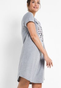 Abito in cotone grigio con maniche corte, scollatura rotonda e un leggero orlo asimmetrico. Presenta una grafica a stampa leopardo in rosa e nero.