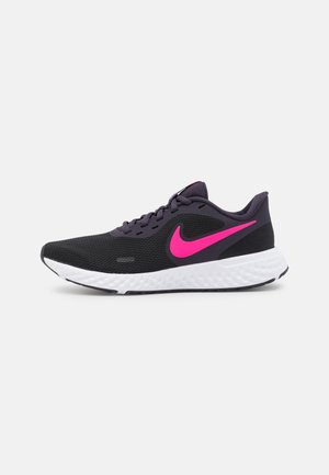 Mustavioletti Nike-juoksukenkä kirkkaan vaaleanpunaisella swoosh-logolla ja valkoisella kuvioidulla pohjalla, sivuprofiilikuva yksinkertaisella harmaalla taustalla.