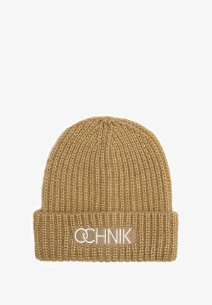 Dzianinowa czapka w jasnobrązowym kolorze z ryflowaną fakturą. Posiada podwinięty mankiet z logo marki wyszytym na biało.
