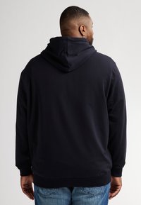 Felpa navy realizzata in morbido cotone, con cappuccio spazioso, maniche lunghe e vestibilità rilassata. Design semplice senza motivi visibili.