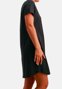 Sort kortærmet kjole med afslappet pasform, lavet af glat stof og med rundet kant, der fremhæver en afslappet silhuet.
