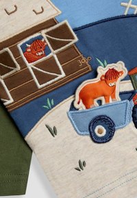 Besticktes Kinderhemd mit einem braunen Stall, einer orangefarbenen Kuh, einem blauen Traktor und grünen Grasdetails; aus weichem Baumwollmaterial mit unterschiedlichen Texturen.