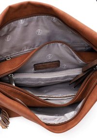 Intérieur d'un sac en tissu marron avec plusieurs compartiments, une poche zippée et une doublure grise ornée d'un motif de logo subtil.