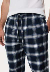 Marineblauwe plaid loungebroeken van zachte stof, met witte en lichtblauwe ruitpatronen, een elastische tailleband en een trekkoord.