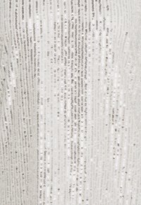 Tessuto argentato con paillettes a strisce verticali, caratterizzato da una texture lucente e una superficie riflettente, che amplifica il gioco di luci. Sottofondo morbido visibile.