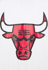 Hvid T-shirt med et stort rød tyr grafik med sorte konturer, der viser bemærkelsesværdige detaljer som ansigtstræk og vinklede horn.