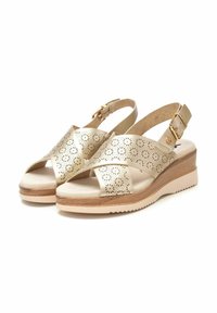 Sandalias beige de cuero perforado, con correas cruzadas y una hebilla. Tacón cuña en material similar a la madera con una suela texturizada.