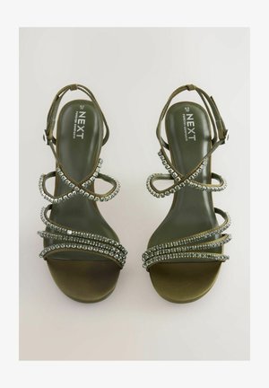 Sandalias de tacón alto verdes con tiras decorativas de rhinestones plateados en las correas y un diseño de puntera redondeada y suave.